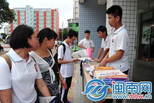 初一初二的学弟学妹在毕业送书摊点前挑选自己想要的 