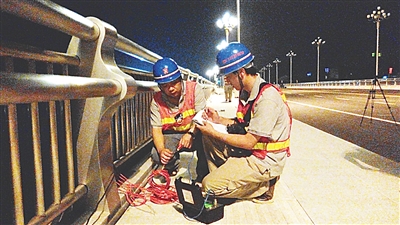 图为技术人员在勘测大桥的相关数据