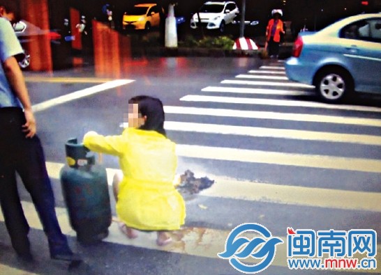 晋江市标附近，女子蹲在人行道用煤气罐烧纸，被民警 