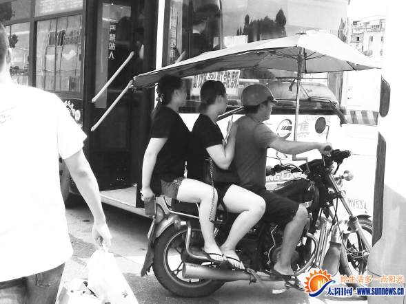 载客摩托车穿梭在公交车缝隙间
