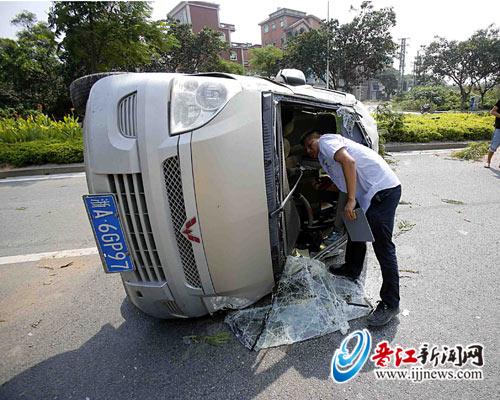 轿车侧翻滚过绿化带“躺”在马路上